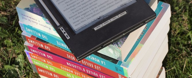 Picture of a stack of books with an eBook reader on top.