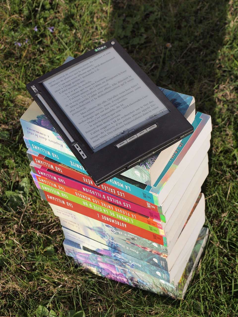 Picture of a stack of books with an eBook reader on top.