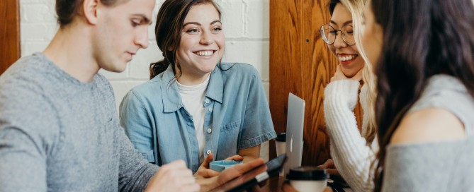 An image of a group of people sitting at a table looking at their devices.