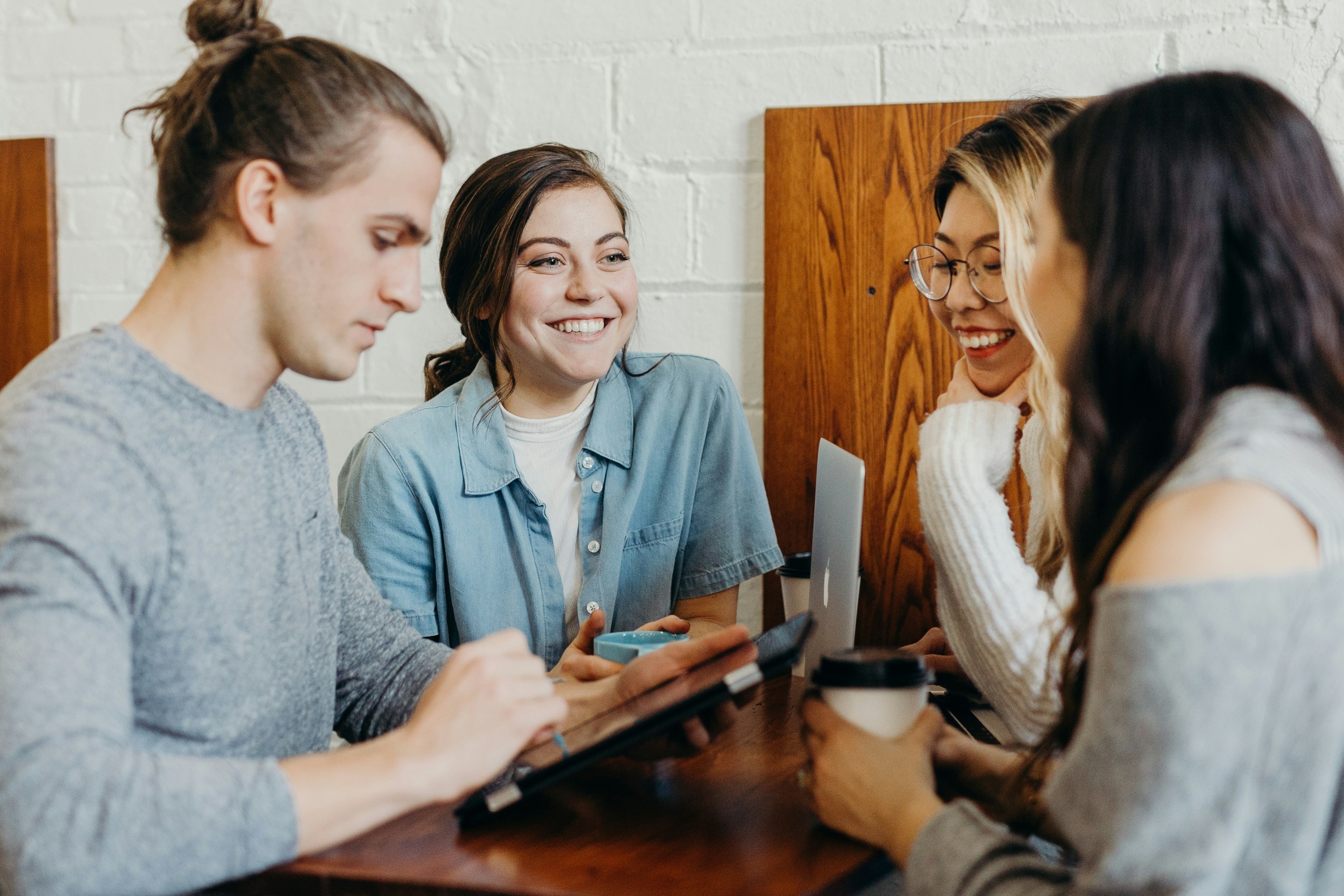 An image of a group of people sitting at a table looking at their devices.